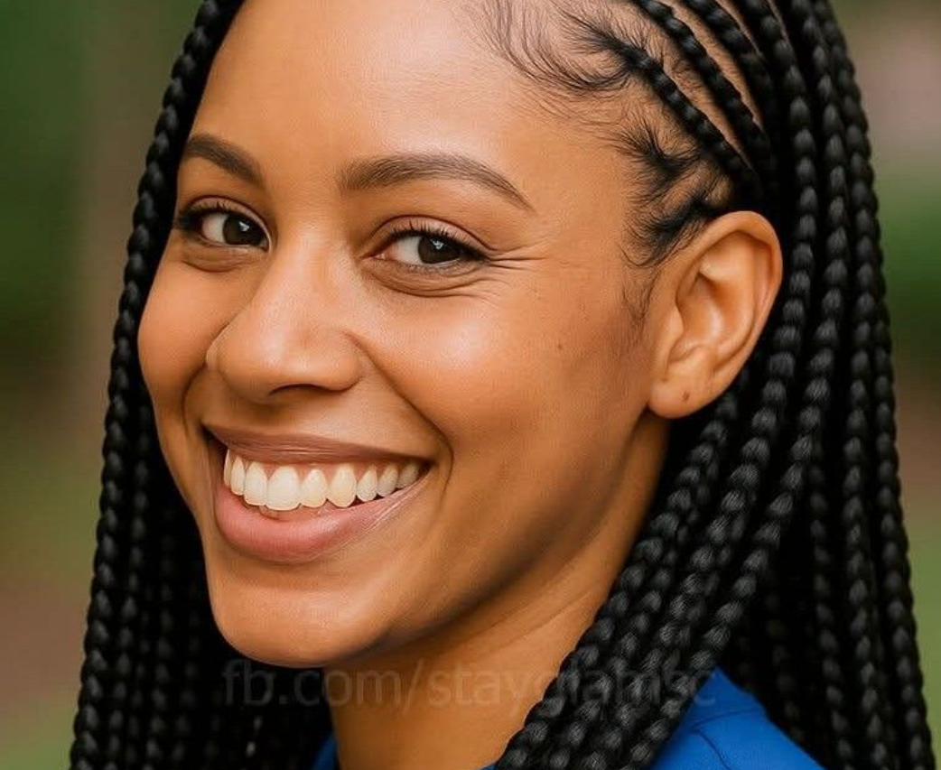 Woman with braided hair smiles, wearing a blue shirt.