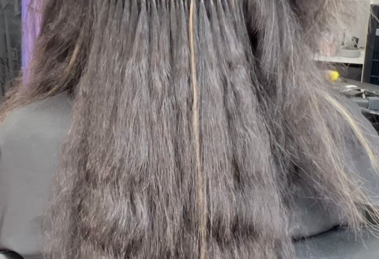 Hair extensions in dark hair, with light streaks and visible attachment points.