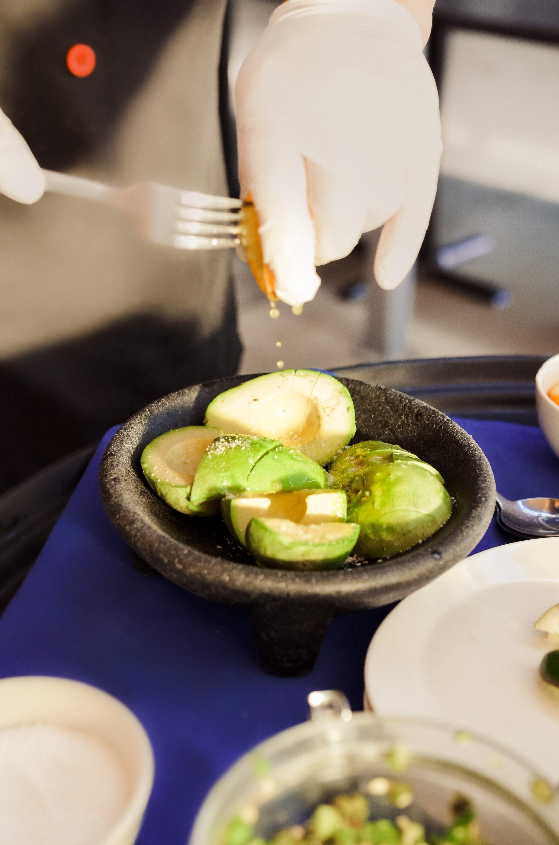 Two people toasting cocktails over a bowl of food.