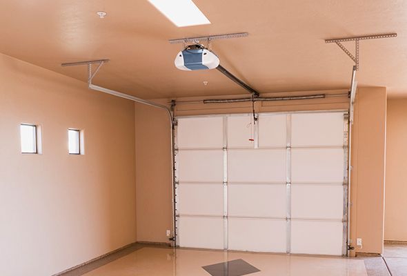 An empty garage with a garage door open and a garage door opener.