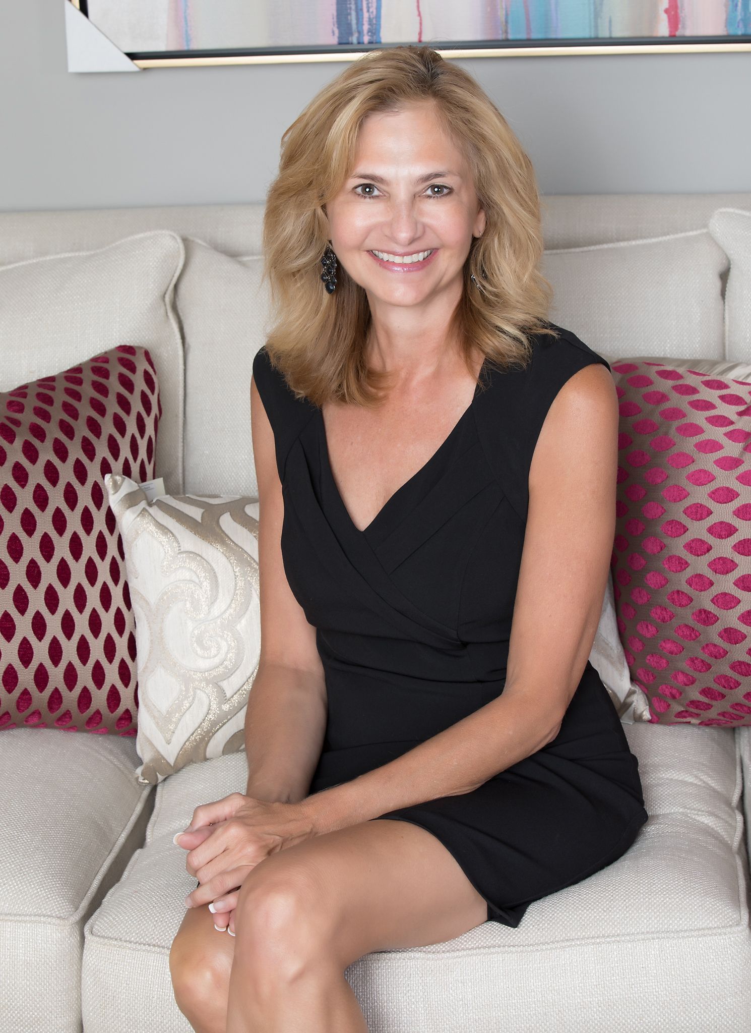 Smiling woman in a black top seated indoors, framed in an oval portrait.