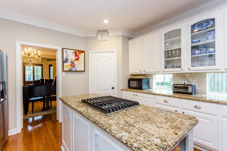 Bright kitchen with white cabinets, granite island, and stainless appliances in a modern home.
