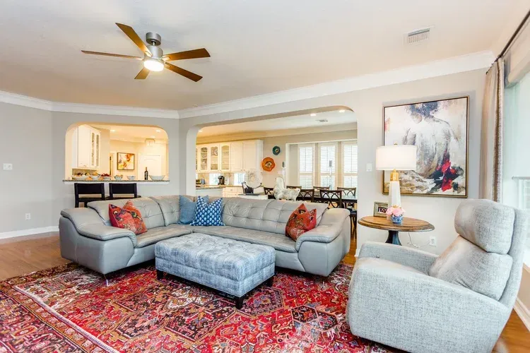 Spacious living room with gray sectional, patterned red rug, recliner, and open view to kitchen and dining area