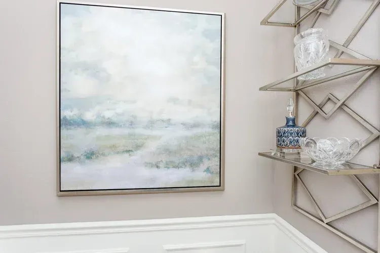 Pastel landscape painting beside a geometric wall shelf with glass decor pieces