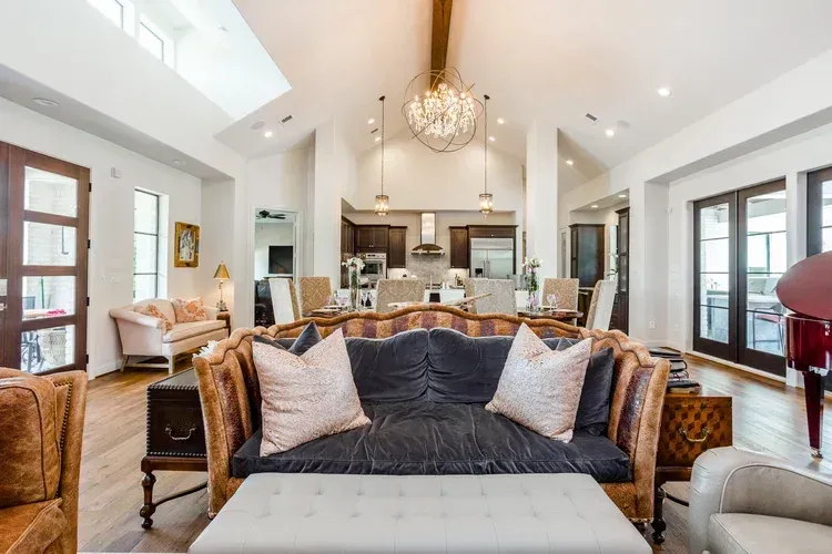 Bright open-concept living room with vaulted ceilings, fireplace, and kitchen island and chandelier in view