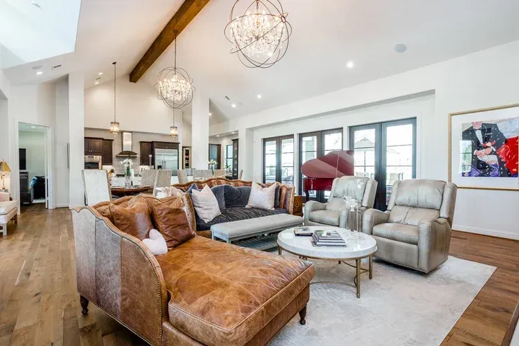 Spacious modern living room with leather seating, white rug, and vaulted ceiling with pendant lights