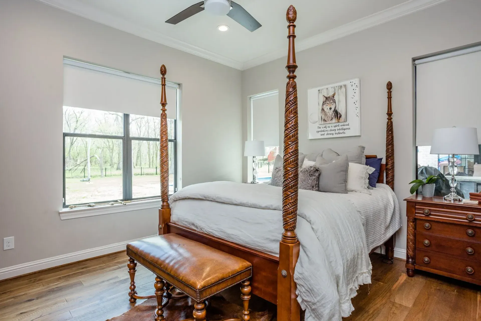Bright bedroom with a four-poster bed, dresser, bench, and large window with natural light