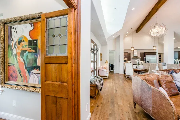 Bright living room with vaulted ceiling, wood beams, and colorful wall art by an entryway