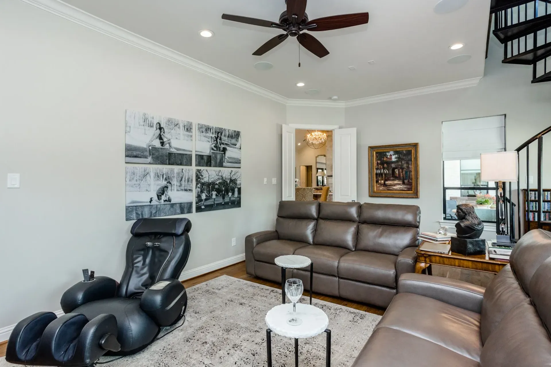 Modern living room with brown leather sofas, black recliner, ceiling fan, and wall art