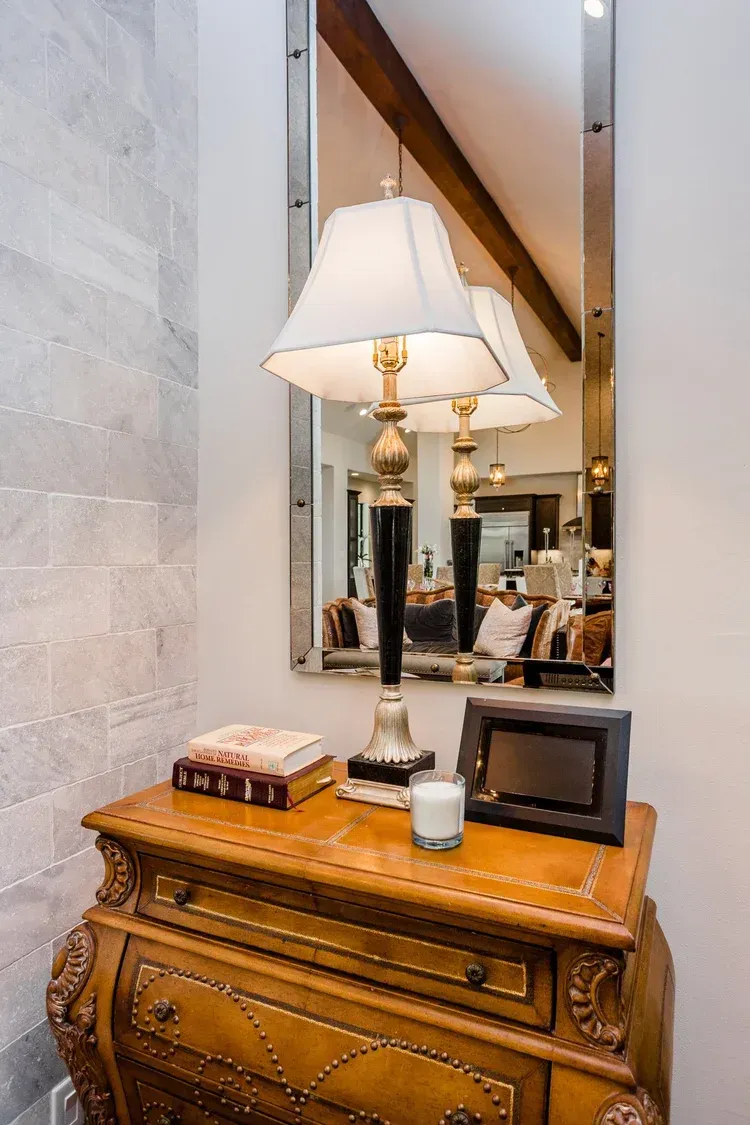 Ornate wooden console table with lamp and mirror in a bright hallway