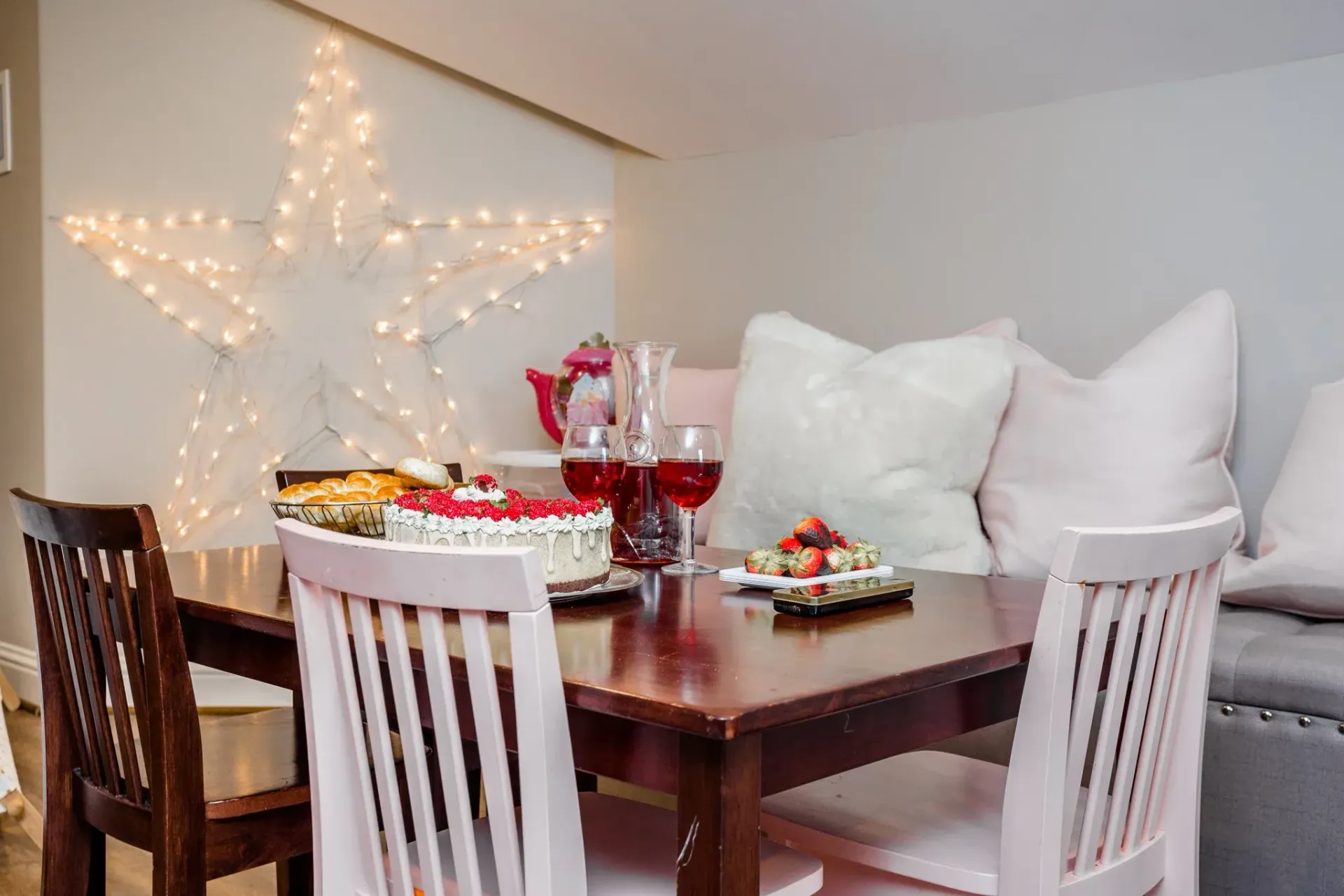 Dining table set with snacks and drinks beside a lit star decoration on the wall