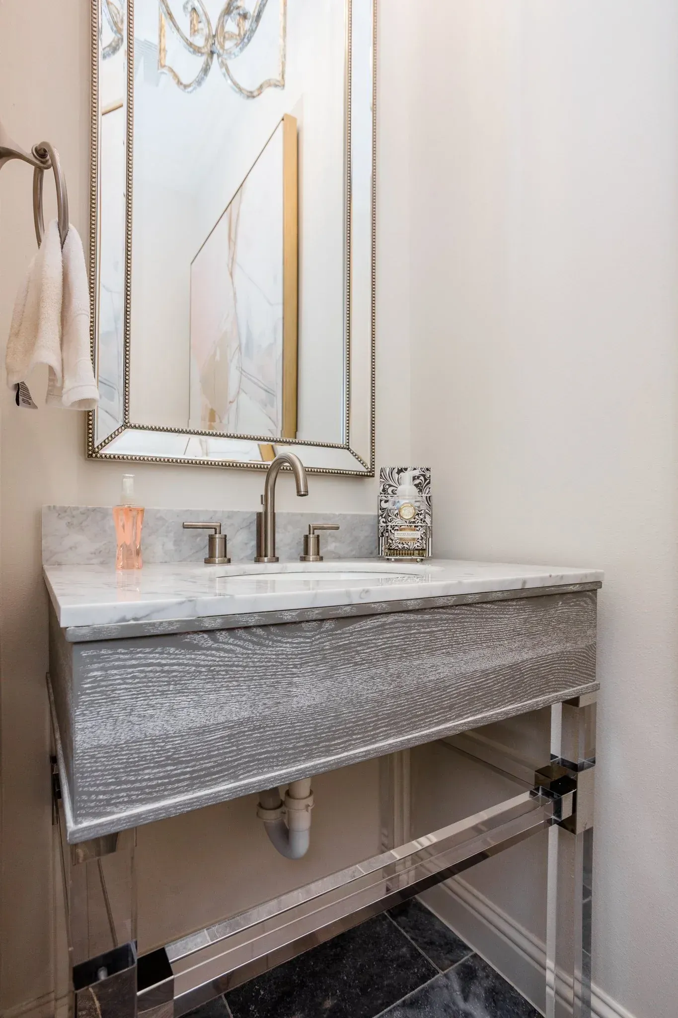 Small modern bathroom vanity with silver sink, mirror, and marble-patterned cabinet