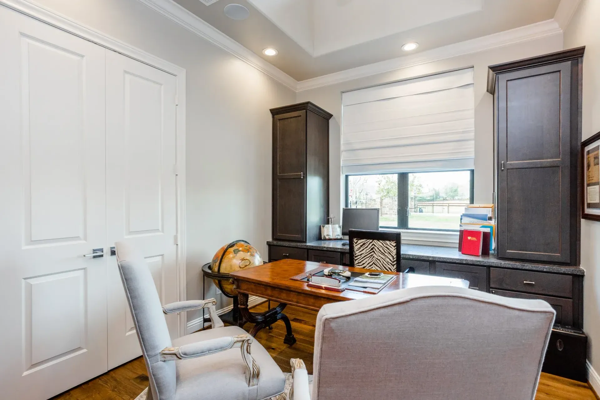 Home office with desk, chair, window, and dark wood cabinets in a bright room