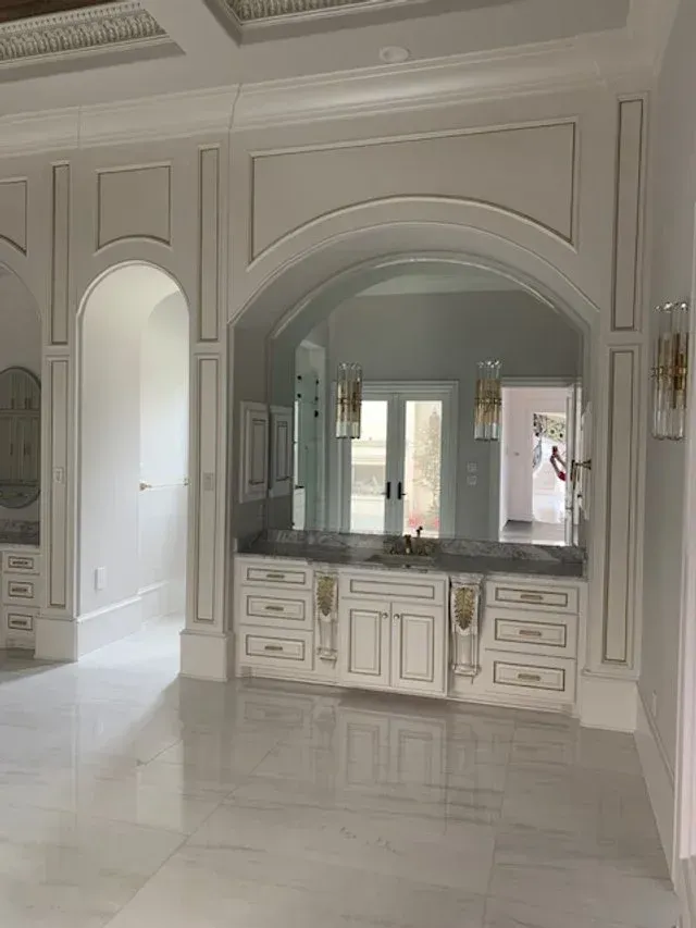 Elegant white interior with arched mirror, built-in cabinetry, and glossy marble floor