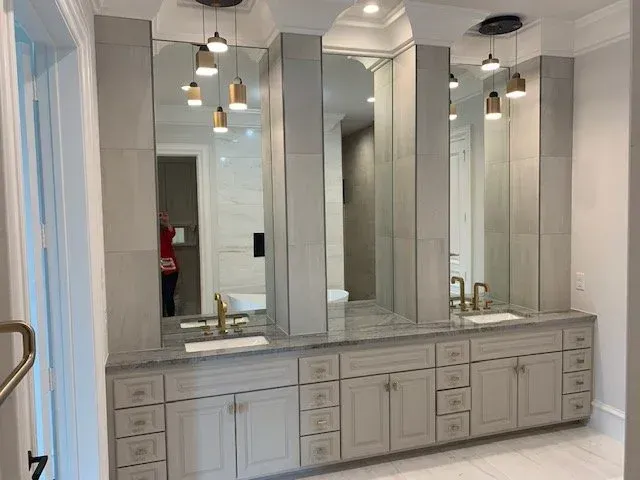 Elegant bathroom vanity with multiple mirrors, pendant lights, and gray cabinetry
