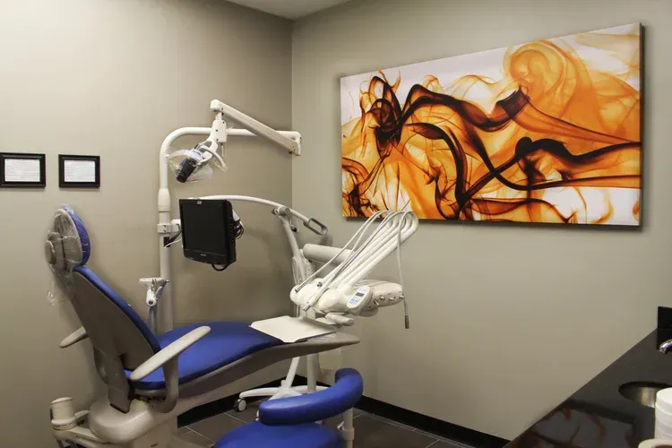 Dental exam room with reclining chair, overhead lamp, and orange abstract wall art
