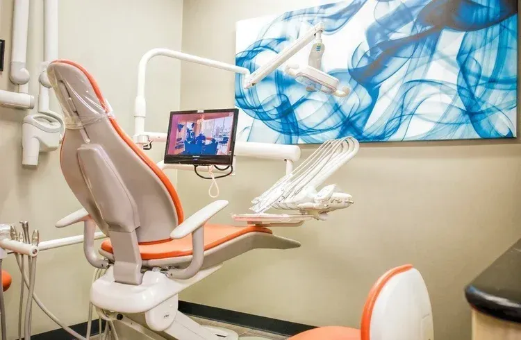 Dental exam chair with monitor in a modern office, accented in orange and white