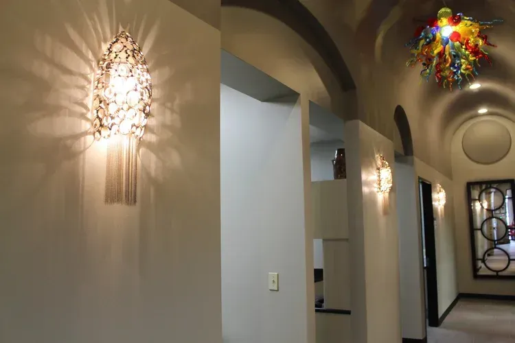 Hallway with arched doorways, wall sconces, and a colorful ceiling light fixture