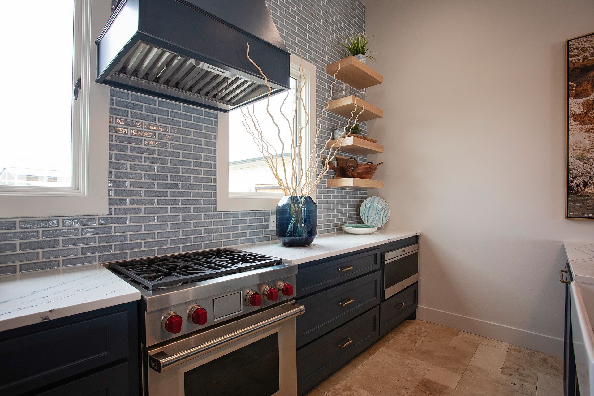Modern kitchen with stainless steel stove, gray tile backsplash, and white countertops