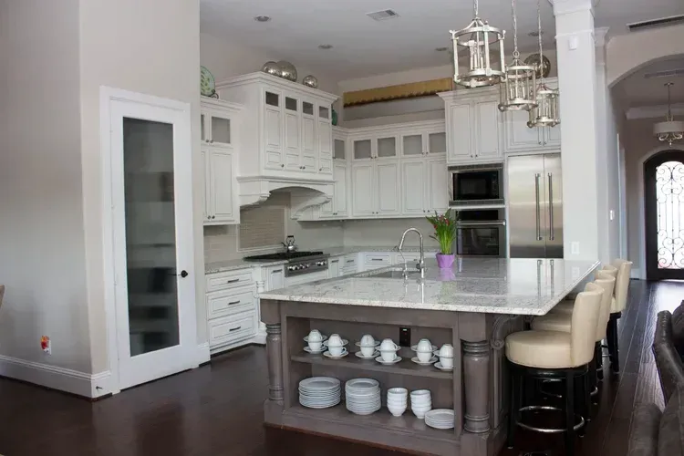 Bright white modern kitchen with marble island, pendant lights, and dark wood floors