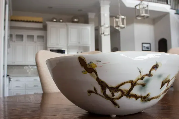 Decorative ceramic bowl on a wooden table in a bright white kitchen