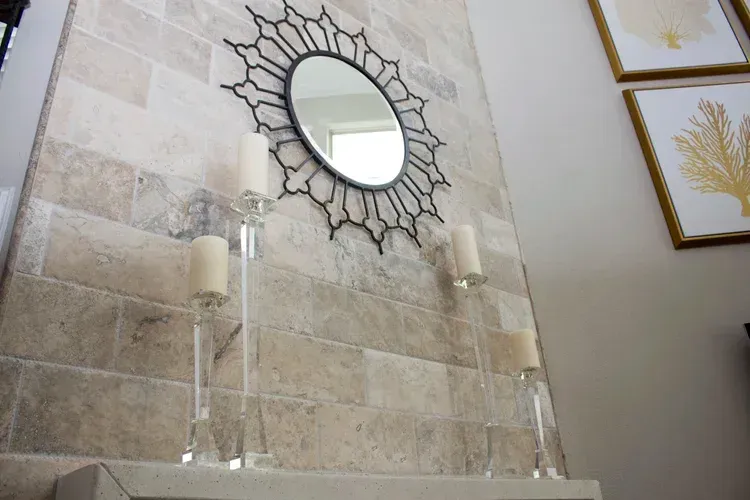 Decorative tiled fireplace wall with a sunburst mirror and two candlesticks above a mantel