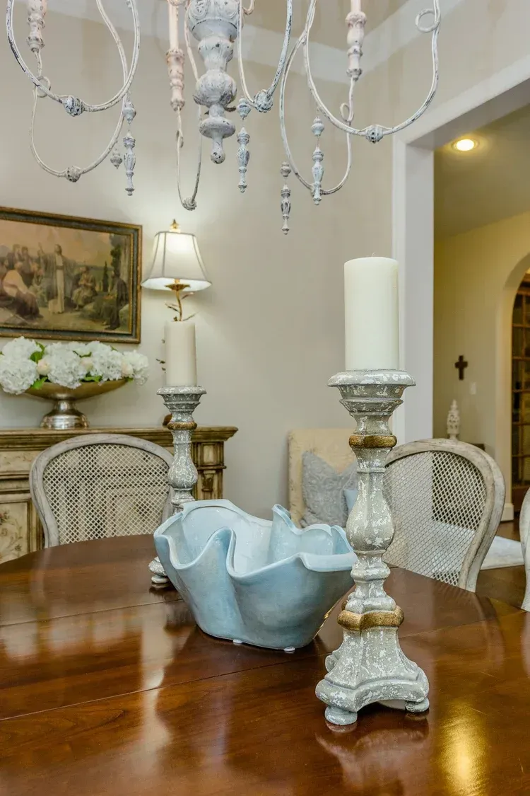 Elegant dining room with chandelier, candlesticks, and a blue bowl on a polished wooden table