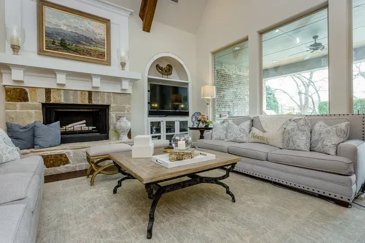 Bright living room with fireplace, large windows, sectional sofas, and a coffee table with decor