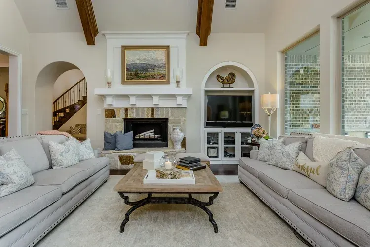 Bright living room with two sofas, fireplace, coffee table, and large windows