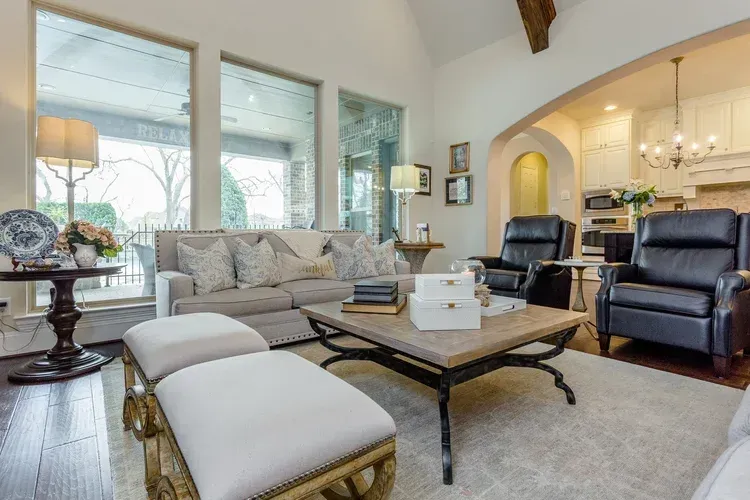 Bright living room with beige sofa, armchairs, coffee table, and large windows