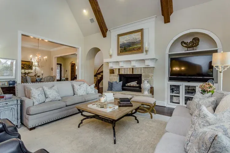 Bright living room with beige sofas, coffee table, fireplace, and TV built into a white arched wall