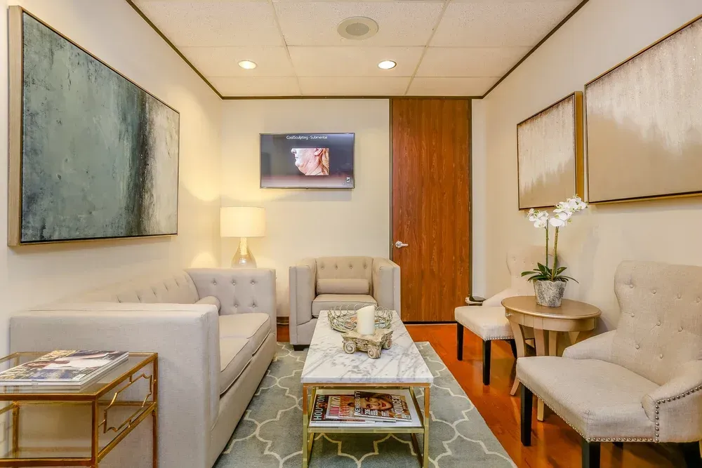 Elegant hotel living room with cream sofas, blue wall art, coffee table, and warm wood accents.