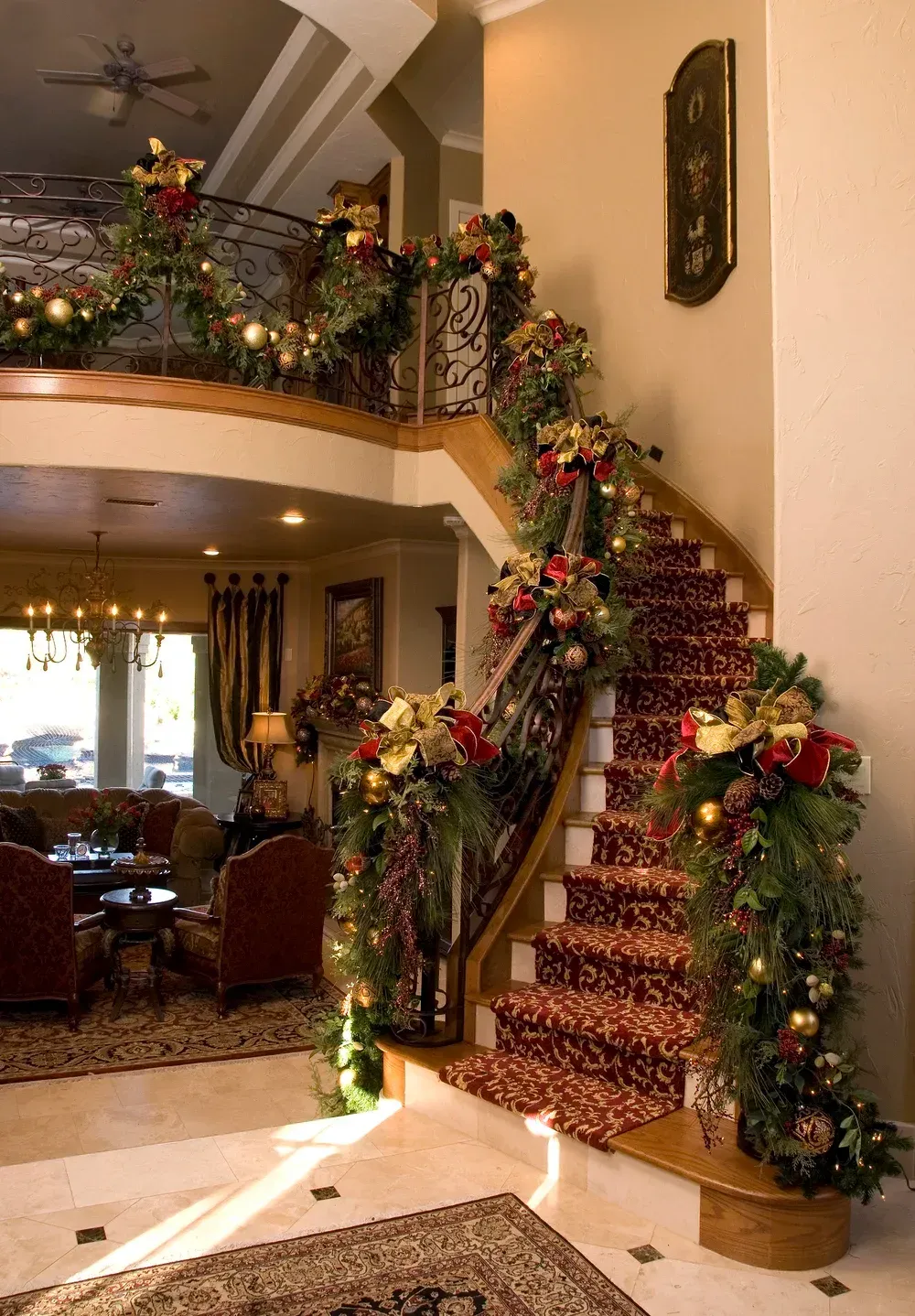 Festively decorated staircase with garlands, flowers, and holiday lights in a spacious home interior