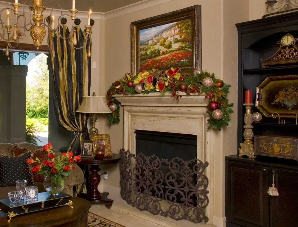 Elegant living room with decorated fireplace, floral garland, dark wood furniture, and ornate mirror