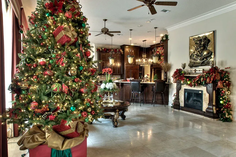 Festively decorated living room with a large Christmas tree, garlands, and a fireplace.
