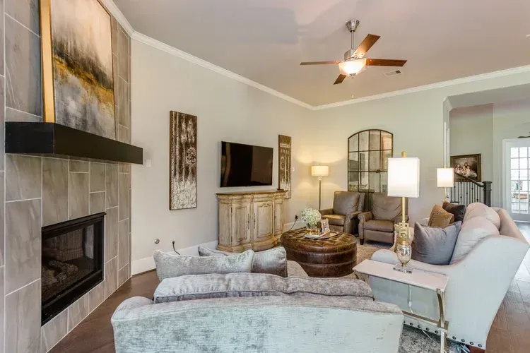 Modern living room with fireplace, TV, beige sofas, and ceiling fan