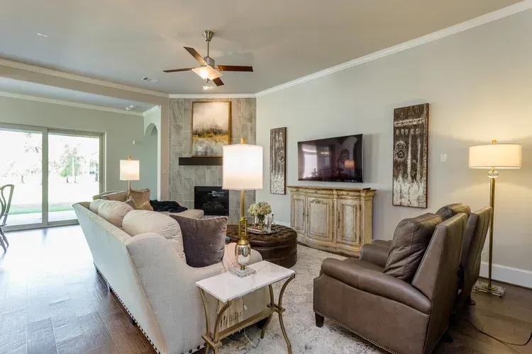 Bright living room with gray sofa, recliner, fireplace, TV, floor lamp, and sliding glass doors