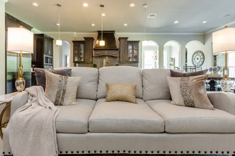 Bright modern living room with a large beige sofa, pendant lights, and arched windows