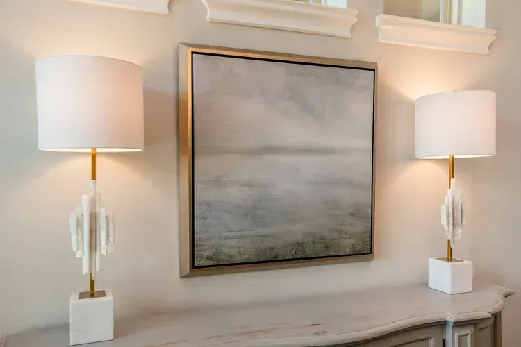 Modern hallway with two lit table lamps flanking a large abstract painting above a console table