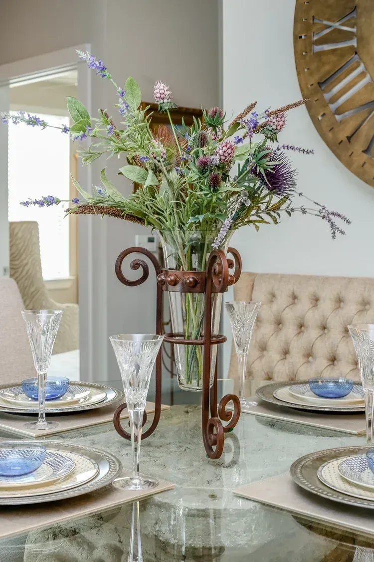 Elegant dining table with floral centerpiece, crystal glasses, and patterned plates in a bright room