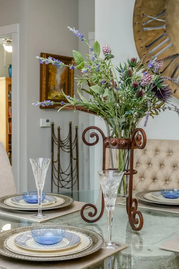 Elegant dining table with floral centerpiece, blue-and-gold plates, and glassware in a bright room