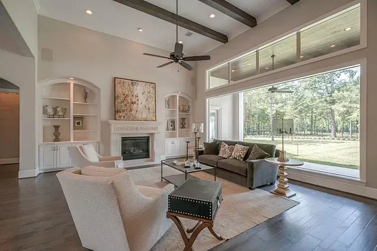 Bright living room with fireplace, vaulted ceiling, and large windows overlooking a grassy yard