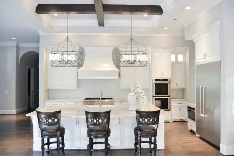 Bright modern kitchen with island, pendant lights, white cabinets, and dark bar stools