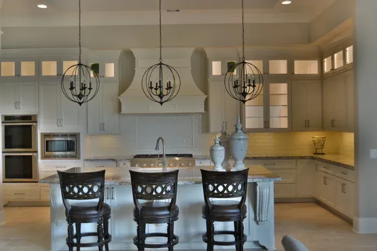 Bright modern kitchen with white cabinets, island, bar stools, and hanging pendant lights
