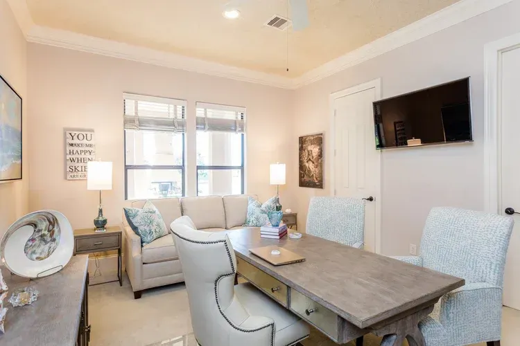 Bright, modern living room with beige sofas, rustic dining table, wall-mounted TV, and soft neutral decor