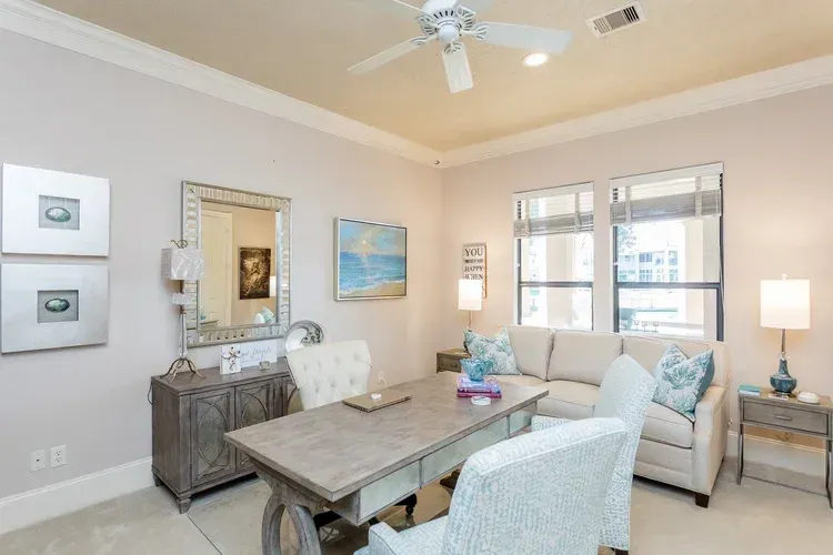 Bright living room with beige walls, white sofa, wooden coffee table, and framed wall art.