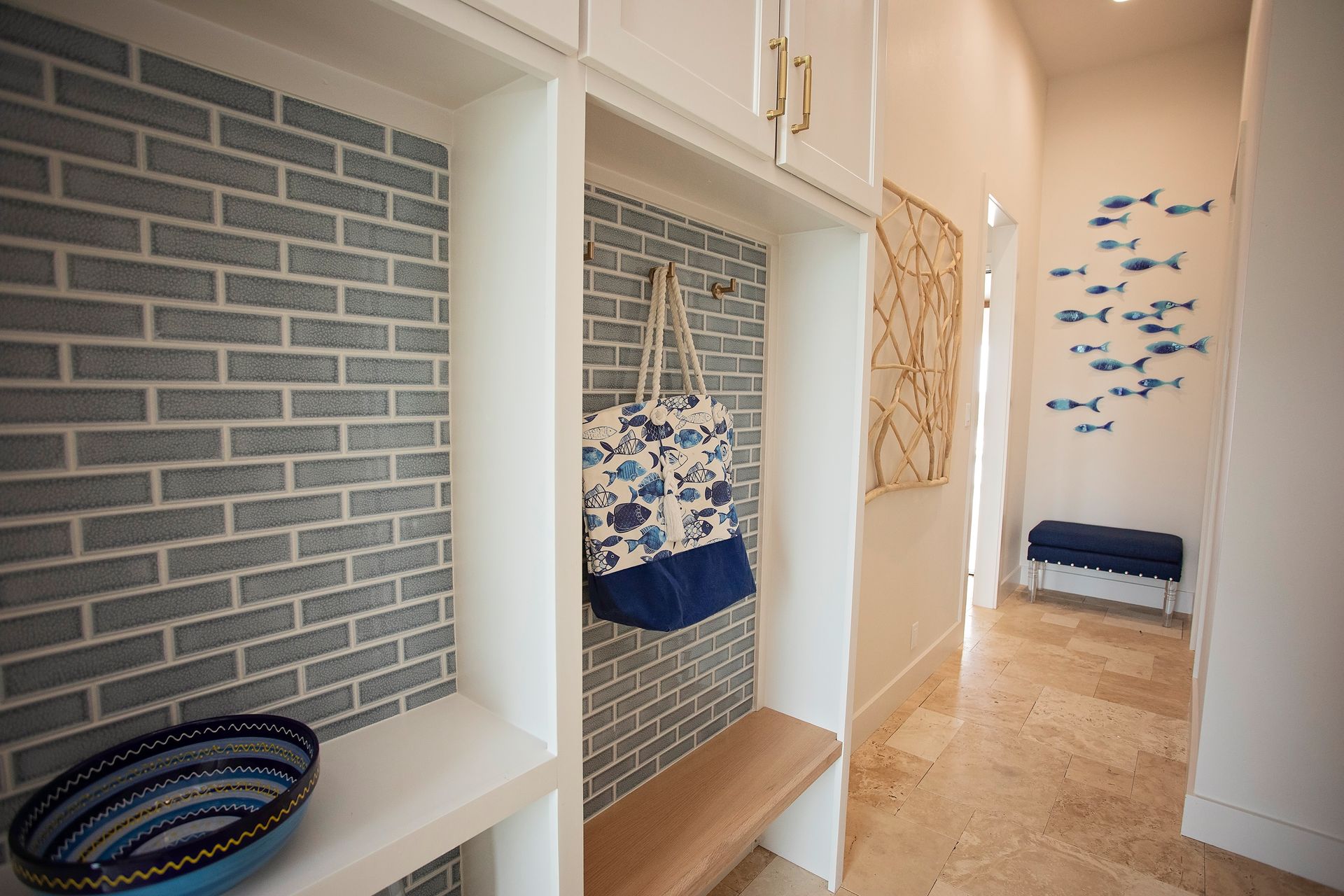 Narrow hallway with white built-in cubbies, blue accents, brick-pattern wallpaper, and a bench at the end.