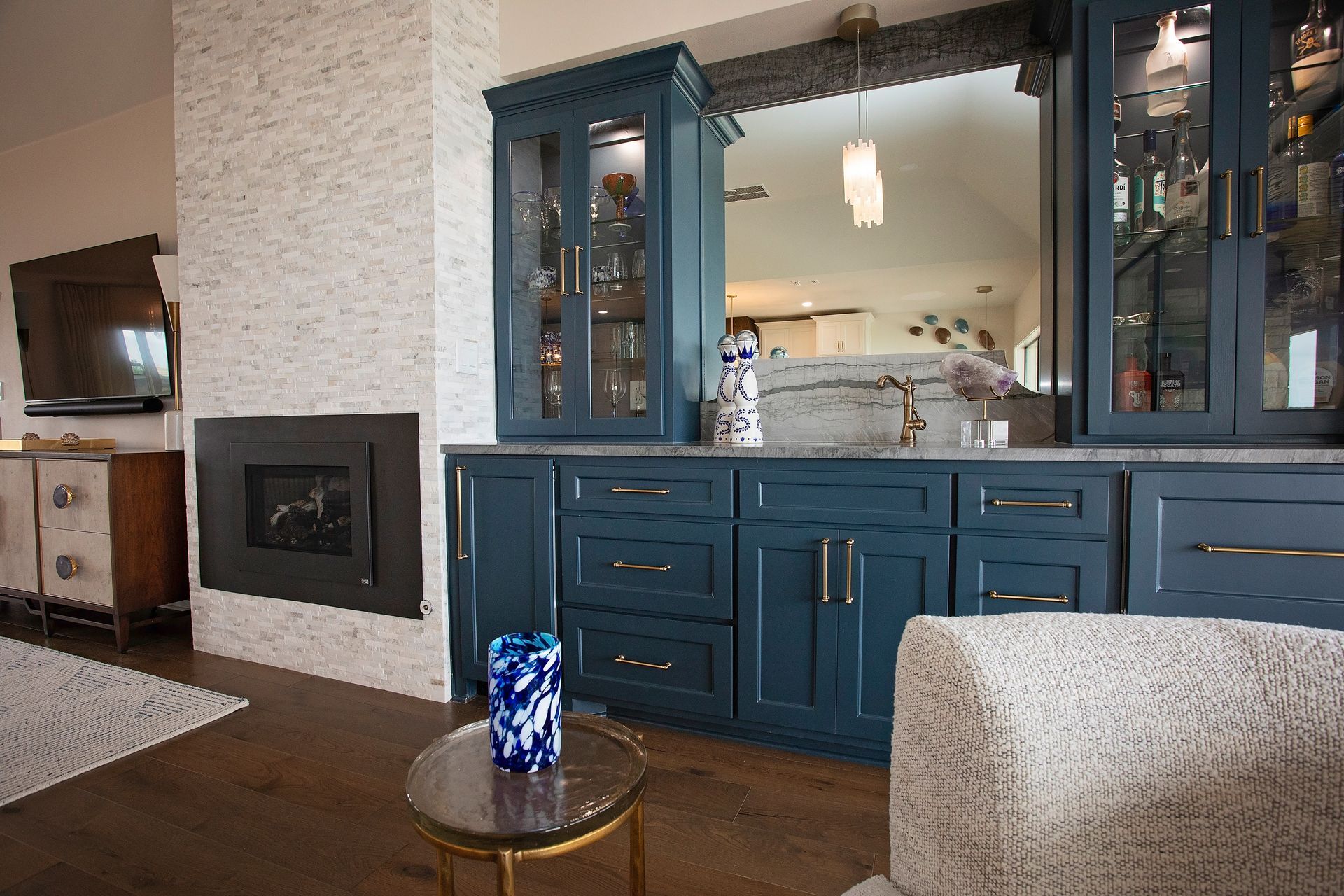 Blue kitchen hutch with glass doors in a living room, beside a fireplace and sofa
