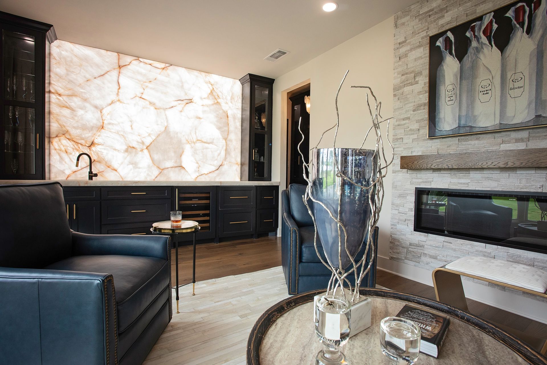 Modern living room with black sofa, marble accent wall, fireplace, and round coffee table