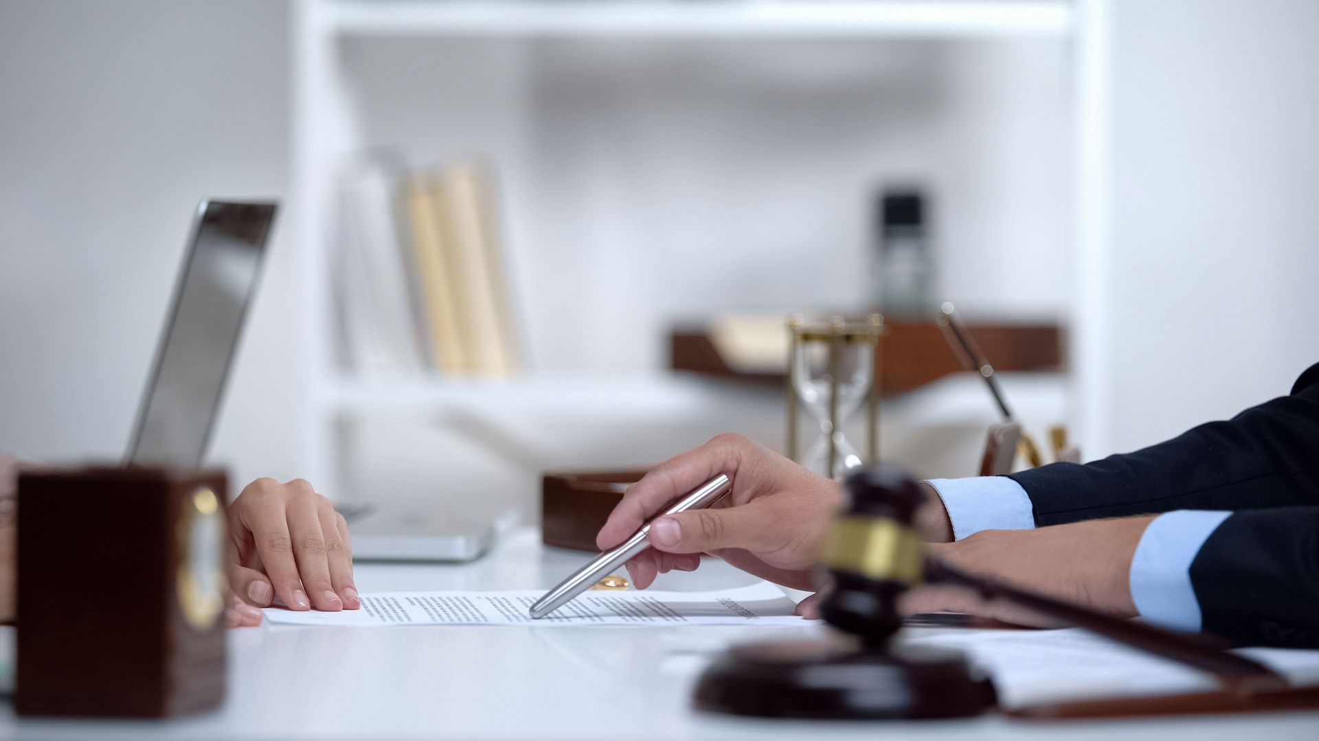 Two people at a desk reviewing a document; a gavel rests on the table.